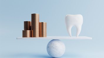 A model tooth and golden coins on a balancing scale on blue background