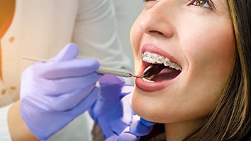 Dentist in blue gloves examining a patient with braces