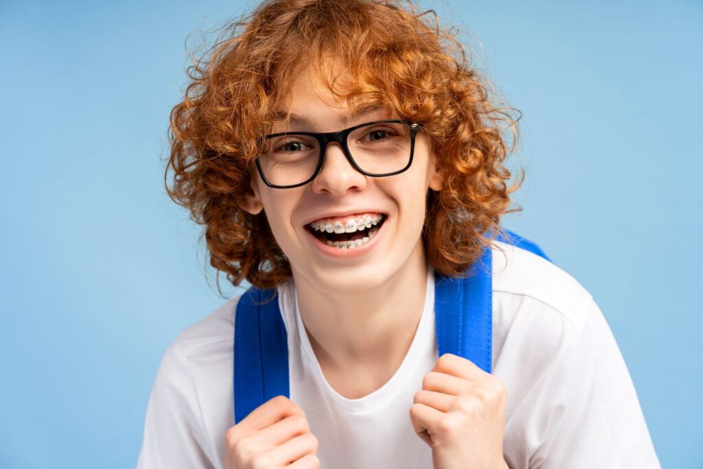 A preteen boy with braces wearing a backpack.