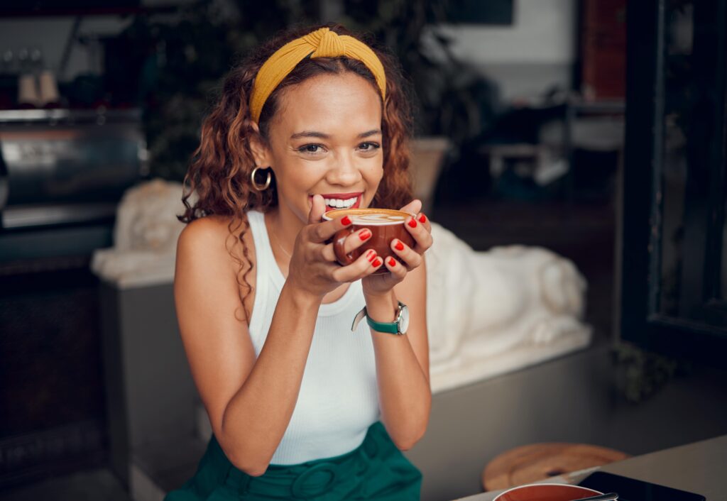 Woman smiling while drinking cup of coffee in cafe